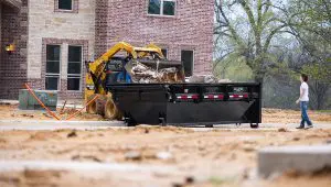 Skid loader dumping scraps into the Roll-Off Dumper Trailer