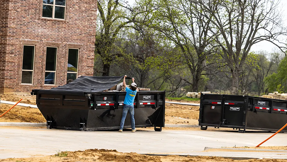 Worker covering a full load in the Roll-Off Dumper Trailer