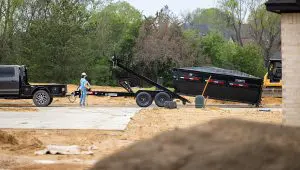 Worker unhitching the Roll-Off Dumper Trailer from a truck