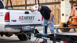 Worker hitching the Single Axle HD Tilt Trailer to a truck