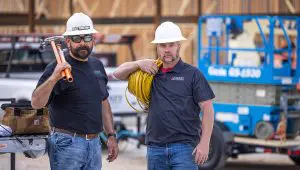 Two electricians standing with the Single Axle HD Tilt Trailer in the background