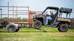 Worker driving an ATV up the loading ramp of the 77