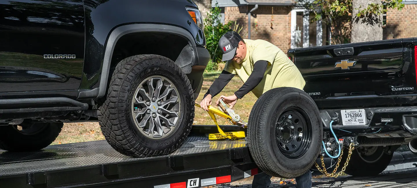 male securing a vehicle to a trailer