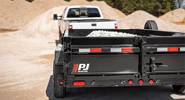 white pickup truck hauling a trailer carrying rocks