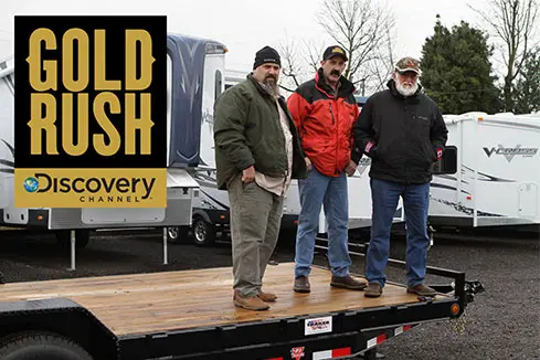 Three stars of the Gold Rush TV show standing on a trailer from PJ Trailers