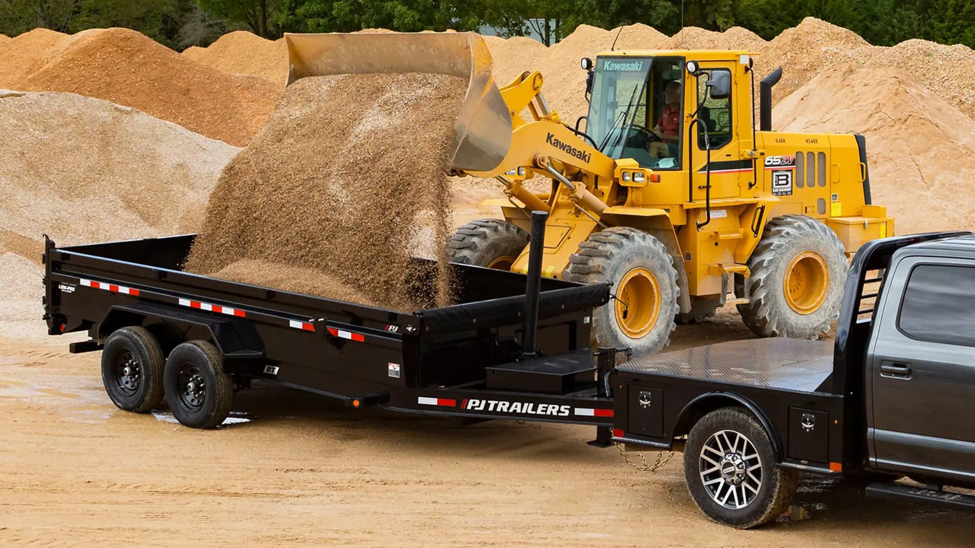 Kawasaki bulldozer dropping a load of aggregate material into the 83