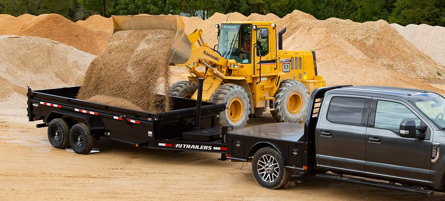 loader loading dirt into trailer hooked to pickup truck