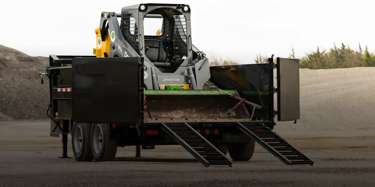 Unloading a John Deere skid steer from the Voyager Dump Trailer (DV)