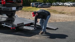 Man lifting the loading ramps on the Steel Deck Car Hauler