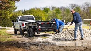 Two men shoveling gravel dumped from the 14K Low-Profile Dump Trailer