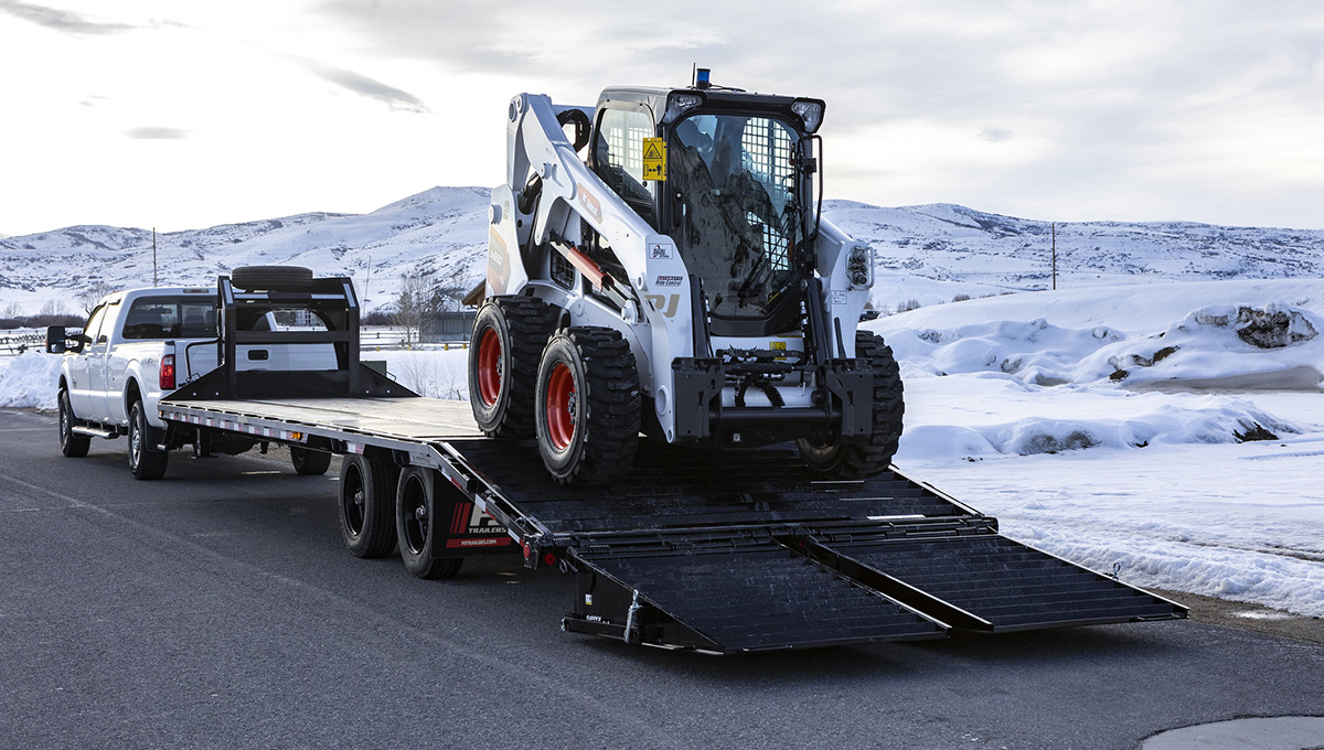 Unloading a skid loader from the Low-Pro Flatdeck Trailer With Duals