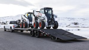 Two skid loaders sitting on the Low-Pro Flatdeck Trailer With Duals
