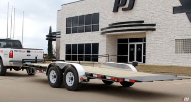 trailer hooked to pickup truck in front of a pj trailers store
